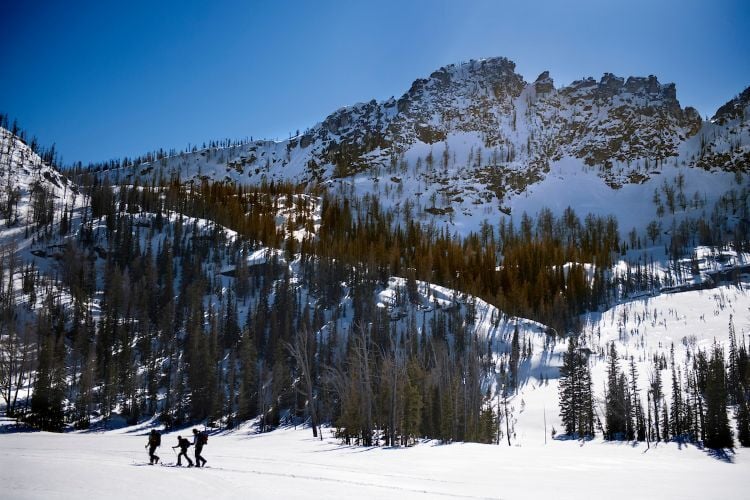 Skiers backcountry ski across Kidney Lake in Montana on a bluebird day