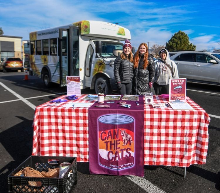Students behind their Can the Cats food donation table