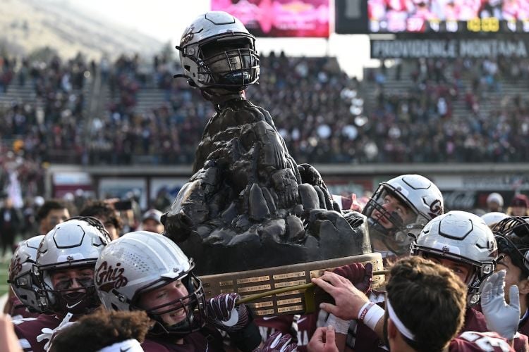 Griz football players hold up the Great Divide Trophy after beating Montana State in the Brawl of the Wild