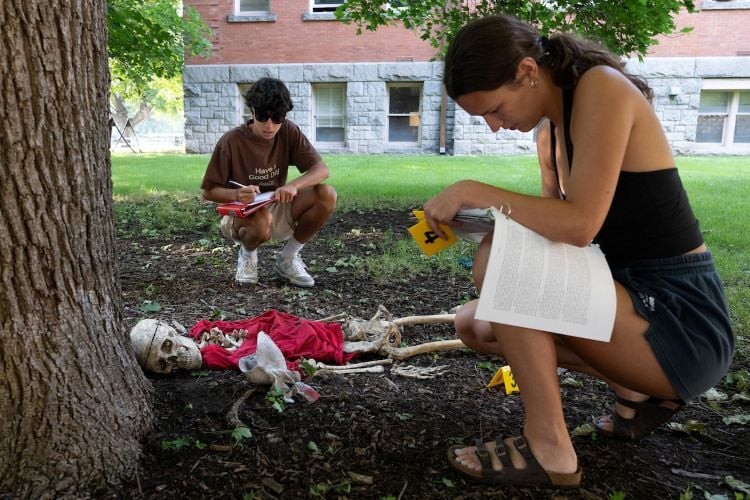 People writing notes over fake crime scene skeleton