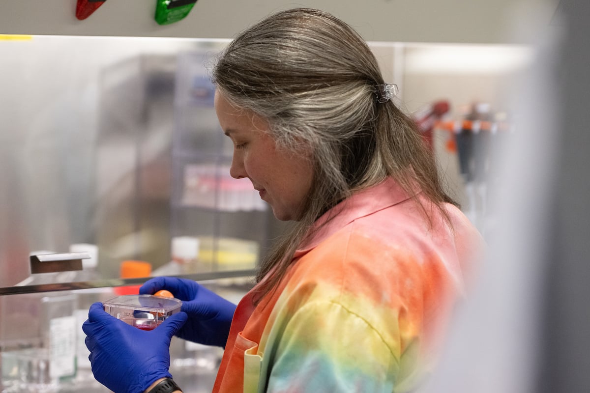 A doctor in a tie-dye lab coat performs research in a laboratory