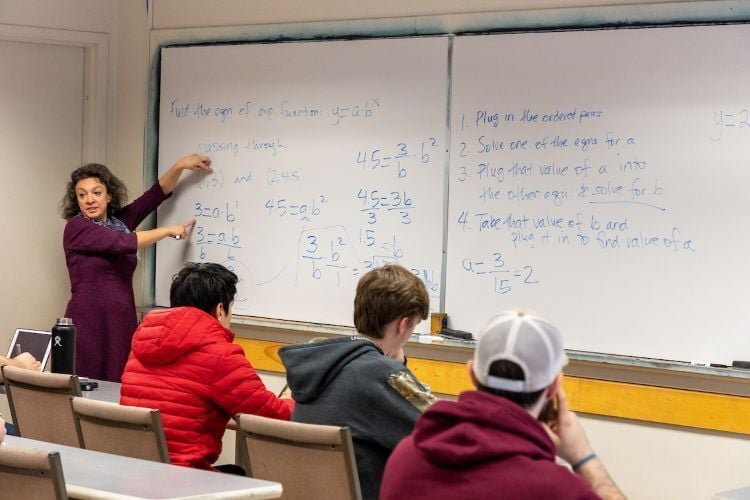 A math teacher in front of a whiteboard teaching class