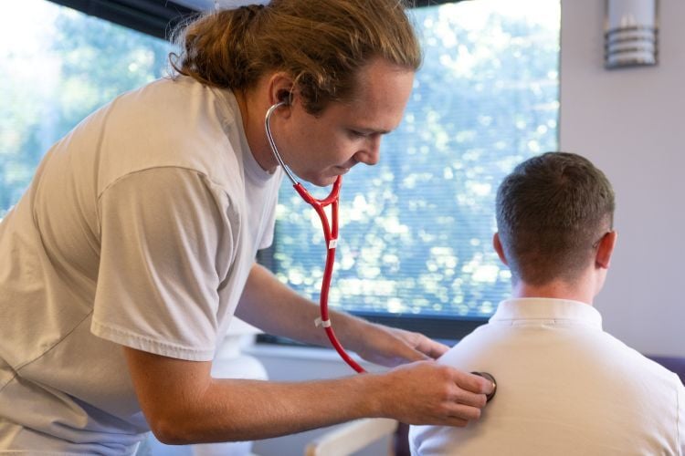 A student doctor uses a stethoscope on another student