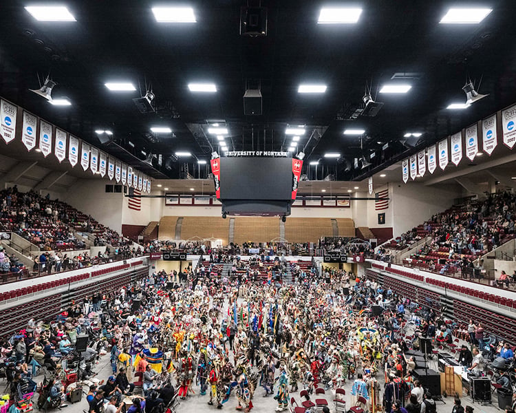 kyiyo powwow with dancers on the floor and people watching from the stands
