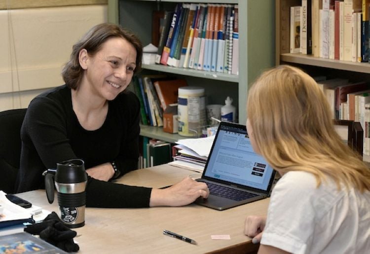 Person working with student showing them something on laptop