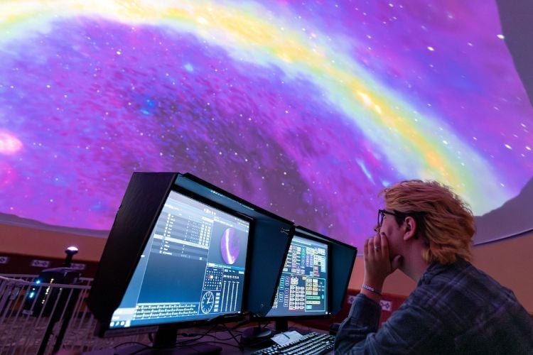 A student sits beneath the UM Planetarium
