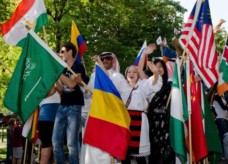 A group of international students participate in UM's homecoming parade, waving flags from across the world.