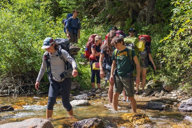 Students backpacking through a creeek
