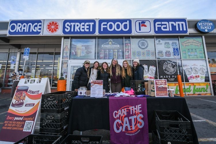 Students standing outside of a grocery store collecting canned goods for a food drive