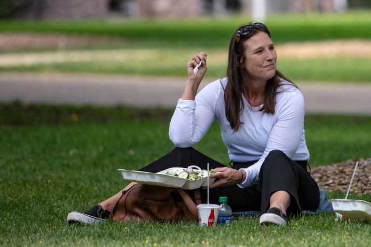 Student eating take-out on the grass of The Oval