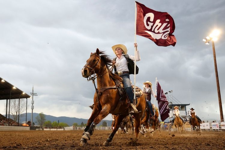 A UM Rodeo Student-Athlete waving the Griz flag atop a horse