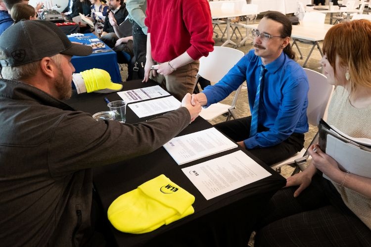 A student shaking hands with an employer at a career fair
