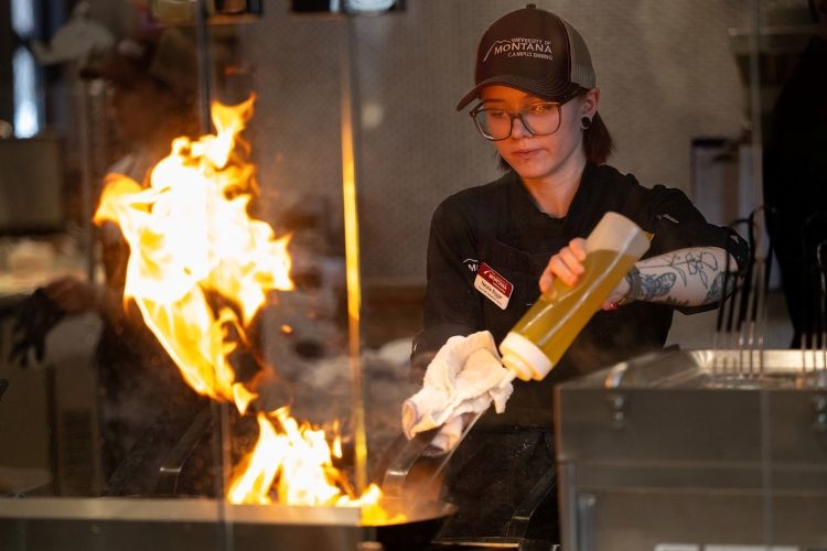 A student worker manages a cook station at The Lodge Dining Center
