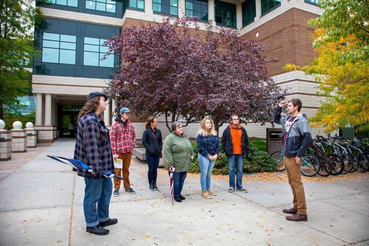 A student leads a campus tour outside of the business building