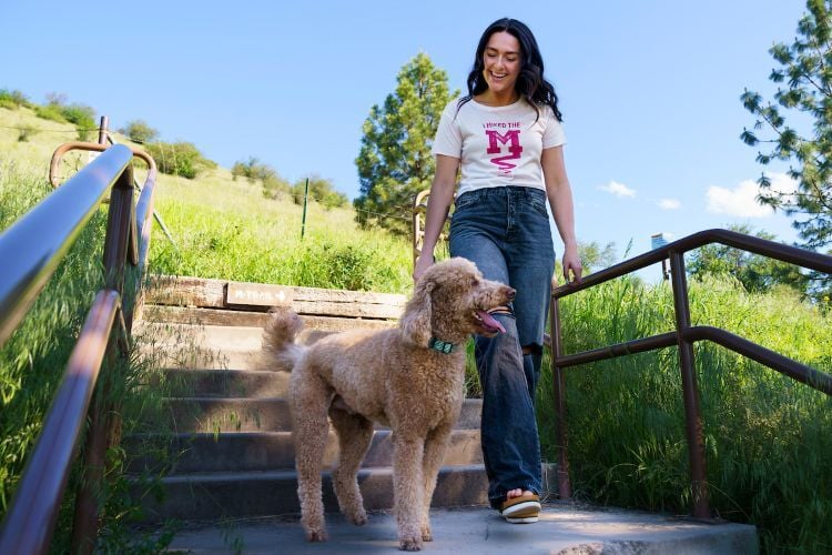 A hiker and her dog descend the "M" trail steps while wearing an "I hiked the "M" trail" t-shirt