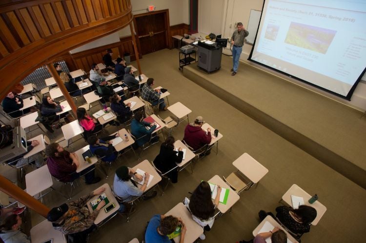 Students fill a classroom with a professor giving a presentation