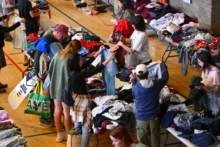 People looking at clothes on a table inside a gym