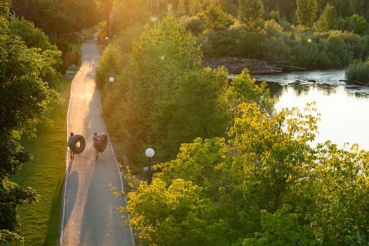 Students walking along the Clark Fork Riverfront Trail with tubes in hand