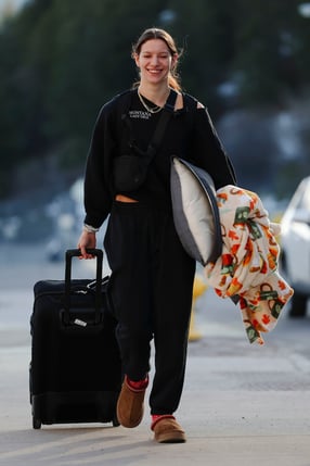 A University of Montana athlete ready to travel with luggage and a pillow and blanket