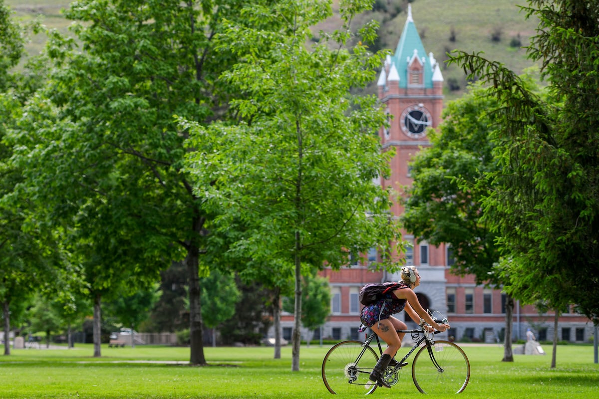 A student rides their bike on The Oval at UM
