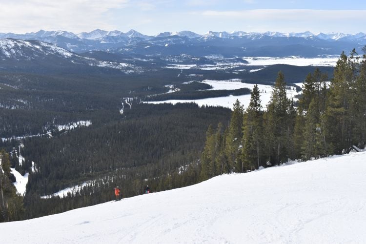 This photo includes a pristine snow covered slop at Discovery Ski Area overlooking Georgetown Lake on a day with blue skies and very limited cloud cover.